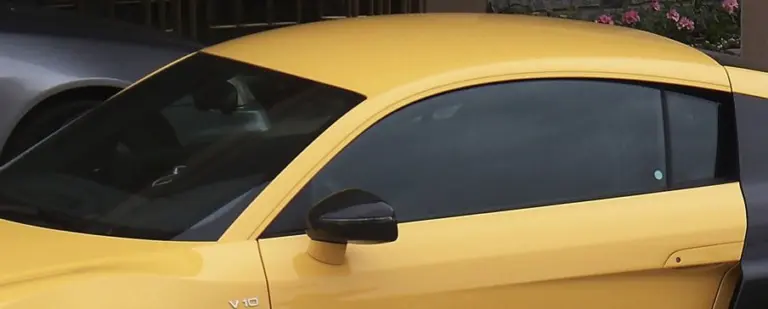 Bright yellow sports car with dark tinted windows and a black side mirror
