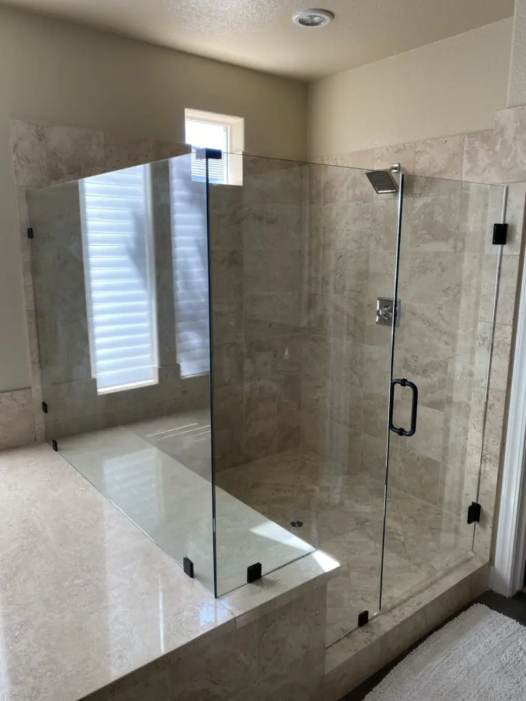 Frameless glass shower enclosure with marble tile surround